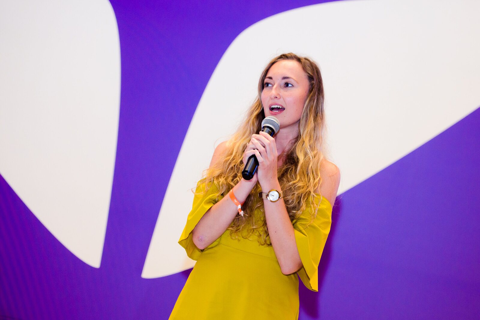 Victoria Puzach speaking on stage with a microphone.